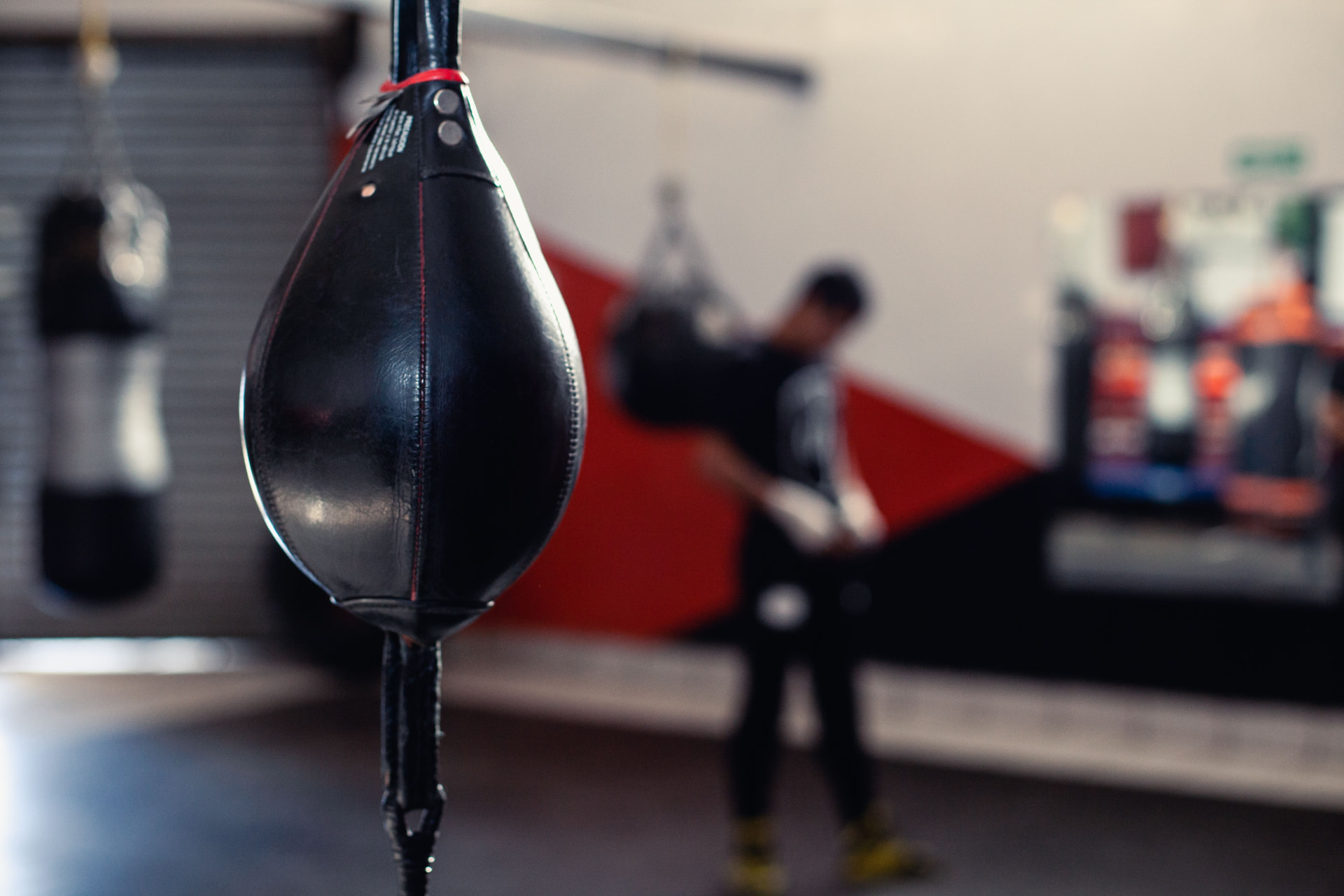 Speed bag hanging in the UpHill gym with a fighter working the heavy bag behind it