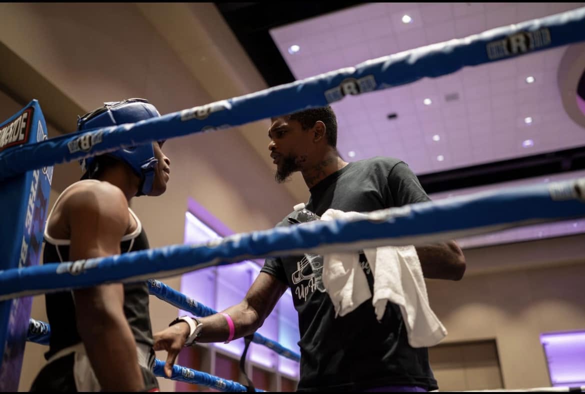 Coach Jalen Hill Sr. talking to a young fighter in the corner between rounds