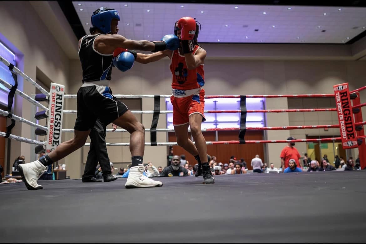 Two young boxers in headgear trading jabs during an amateur bout